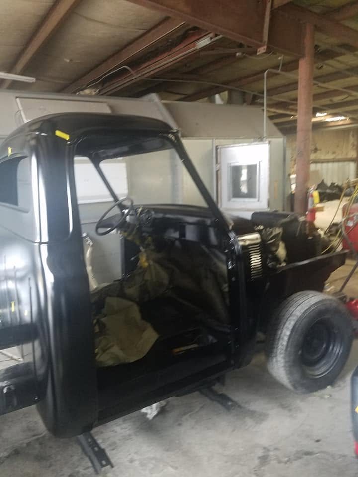 Side view of a classic pickup cab painted black, with the interior masked off
